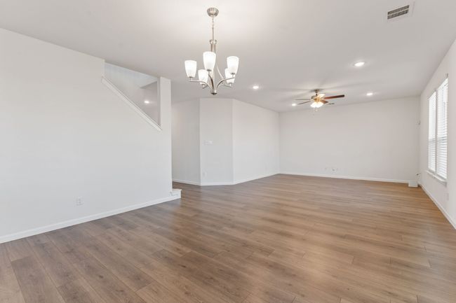 Unfurnished room with visible vents, baseboards, light wood-style flooring, recessed lighting, and ceiling fan with notable chandelier | Image 4