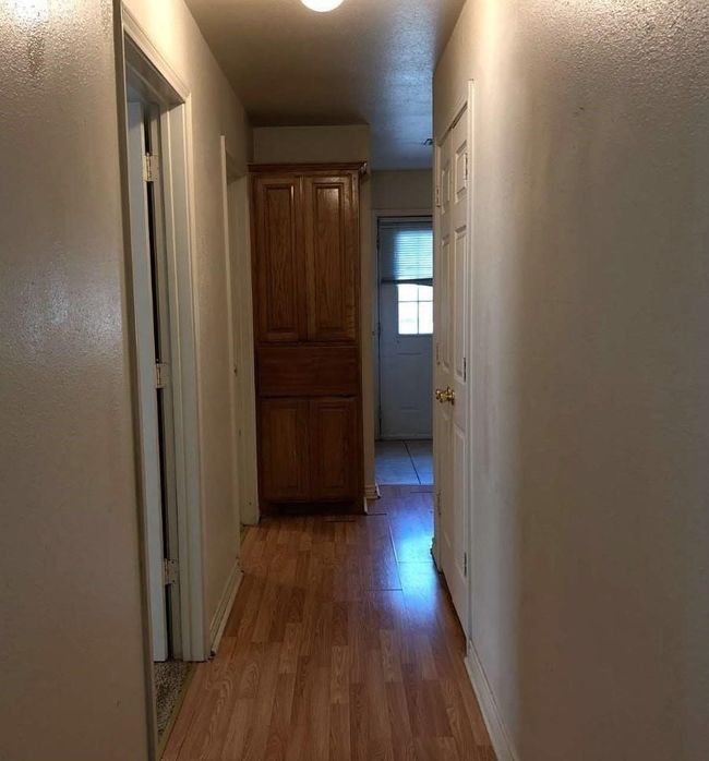Hallway with light wood-type flooring and baseboards | Image 7