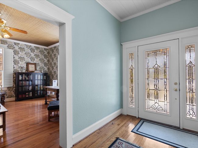 Foyer entrance featuring a ceiling fan, crown molding, baseboards, and wood finished floors | Image 23
