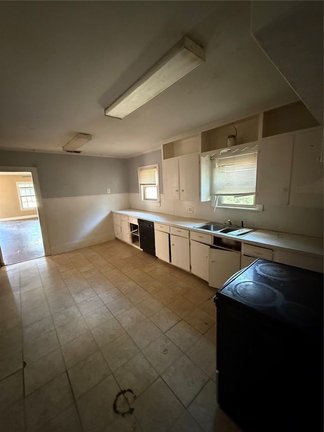 Kitchen featuring stove, white cabinetry, light countertops, and plenty of natural light | Image 11