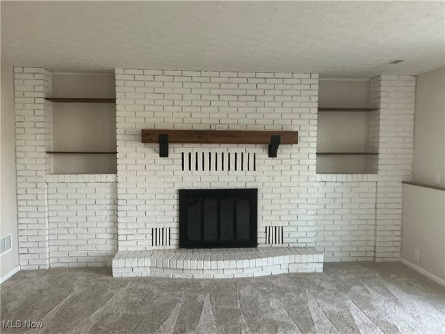 Unfurnished living room featuring a fireplace, a textured ceiling, and carpet floors | Image 5