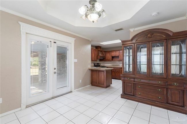 Kitchen with french doors, a chandelier, a peninsula, range, and light countertops | Image 7