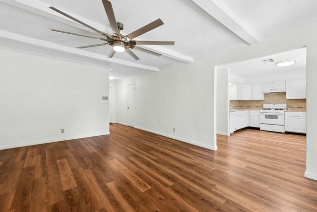 Living room with beamed ceiling, a ceiling fan, and wood finished floors | Image 7