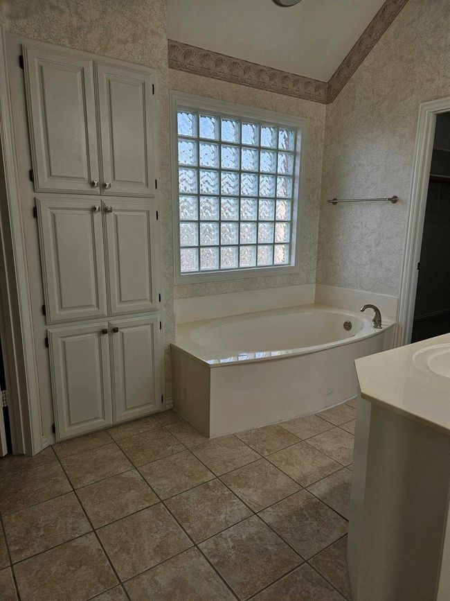 Bathroom with a garden tub, vanity, a closet, and tile patterned flooring | Image 13