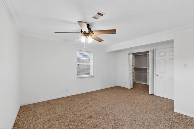 Unfurnished bedroom featuring ornamental molding, carpet flooring, ceiling fan, a walk in closet, and a closet | Image 27