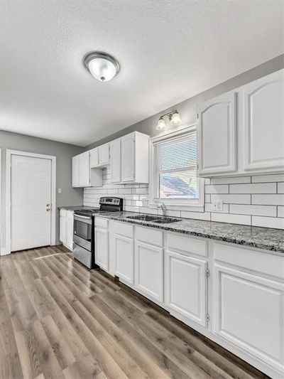 Kitchen featuring light hardwood / wood-style flooring, white cabinets, sink, and stainless steel electric range | Image 3