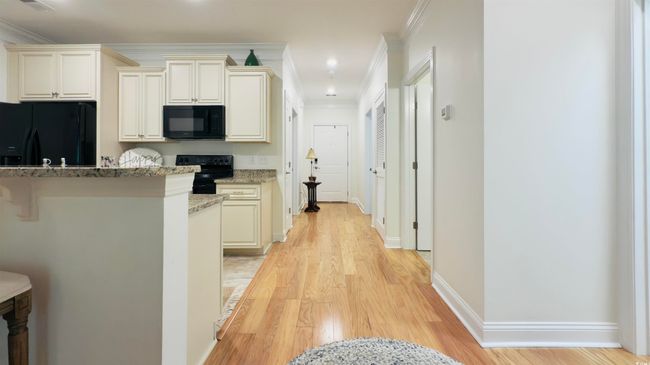 Kitchen featuring black appliances, light wood-style floors, light stone counters, and crown molding | Image 15