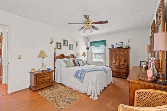 Bedroom with light wood-style floors, a textured ceiling, and a ceiling fan | Image 12