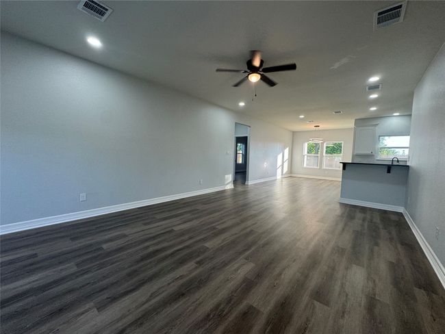 Unfurnished living room with ceiling fan, dark wood finished floors, and recessed lighting | Image 4