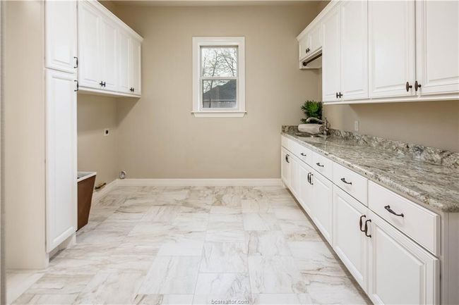 Laundry room with electric dryer hookup, cabinet space, a sink, baseboards, and marble finish floor | Image 21