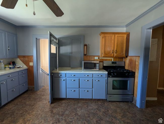 Kitchen with wooden walls, stainless steel appliances, light countertops, and a wainscoted wall | Image 6