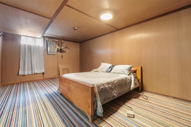 Bedroom with carpet floors, wood walls, wood ceiling, and electric panel | Image 30