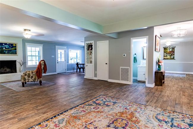 View from living area toward den, fireplace, breakfast area, guest bath, foyer and dining room. The closed door is access to storage area under the stairway. | Image 33