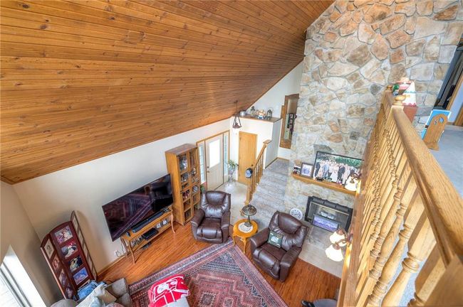 Living area featuring lofted ceiling, wooden ceiling, a fireplace, and wood finished floors | Image 27