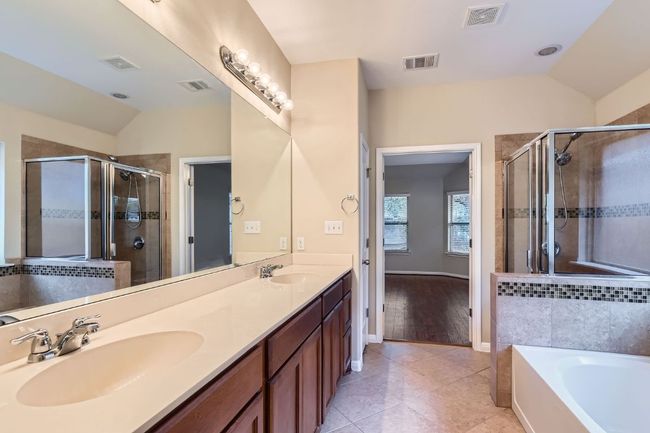 Primary Full bath featuring vaulted ceiling, a bath, a shower stall, double vanity, and tile patterned flooring | Image 21