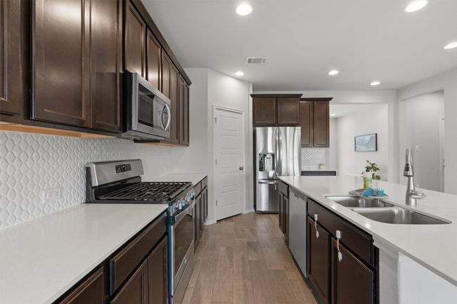 Stainless steel appliances, a lovely tile backsplash, and tile flooring throughout. | Image 9