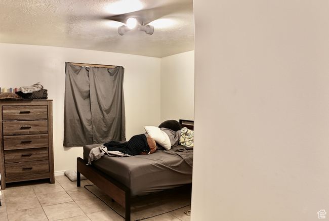 Bedroom with light tile patterned floors, ceiling fan, and a textured ceiling | Image 42