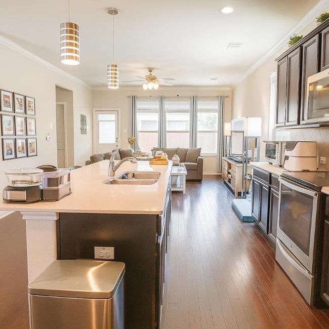 Kitchen featuring appliances with stainless steel finishes, open floor plan, light countertops, a kitchen island with sink, and dark brown cabinets | Image 5