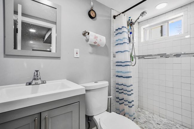 Bathroom featuring a tile shower, toilet, and vanity | Image 8