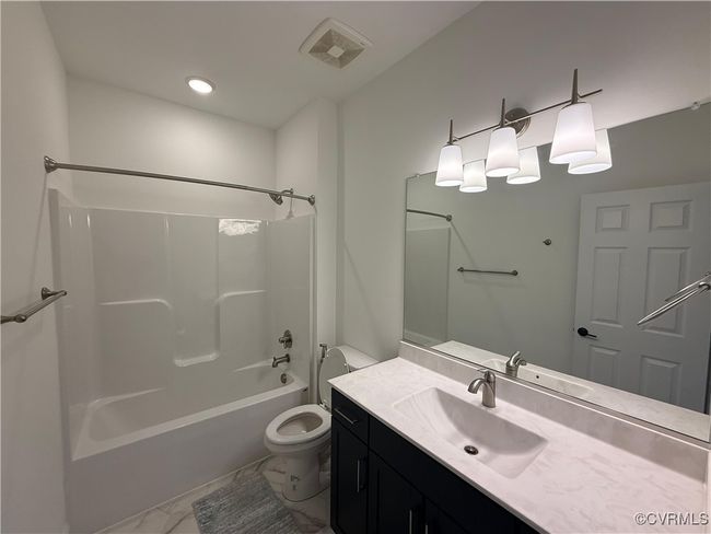 Bathroom featuring marble look tiles, vanity, toilet, shower / bath combination, and recessed lighting | Image 15