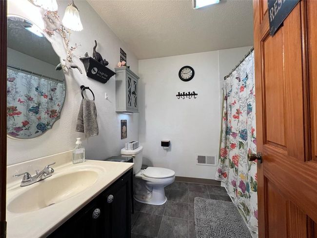 Bathroom featuring vanity, toilet, baseboards, a textured ceiling, and tile patterned floors | Image 9
