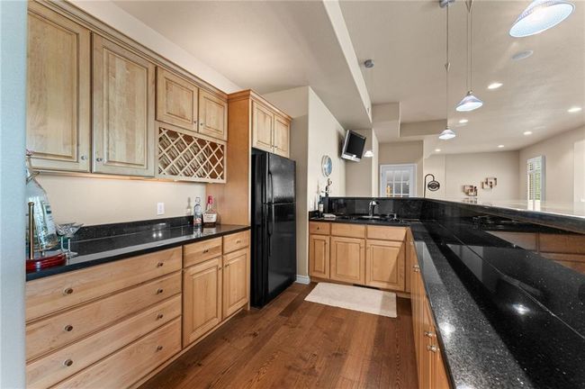 Kitchen featuring a sink, dark stone countertops, dark wood-type flooring, pendant lighting, and freestanding refrigerator | Image 40