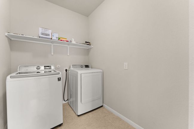 Laundry room with independent washer and dryer, light tile patterned floors, and baseboards | Image 18