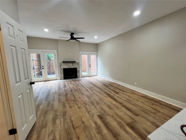 Unfurnished living room featuring french doors, baseboards, wood finished floors, ceiling fan, and recessed lighting | Image 8