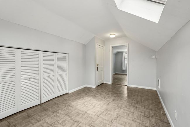 Unfurnished bedroom featuring a closet, baseboards, and lofted ceiling with skylight | Image 16