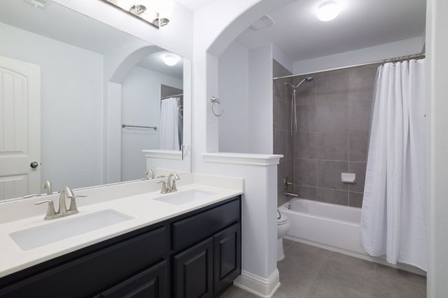 Full bathroom featuring tile patterned flooring, double vanity, toilet, and shower / tub combo | Image 27