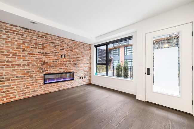 Unfurnished living room featuring a brick fireplace and dark wood-style flooring | Image 13