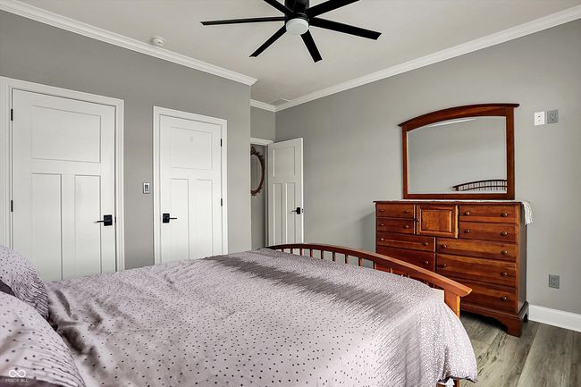 bedroom with a ceiling fan, baseboards, ornamental molding, and wood finished floors | Image 34