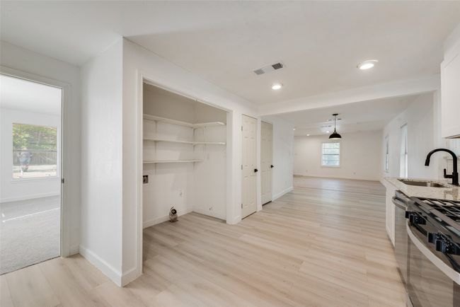 Clothes washing area with light wood-style flooring, visible vents, baseboards, and a sink | Image 12