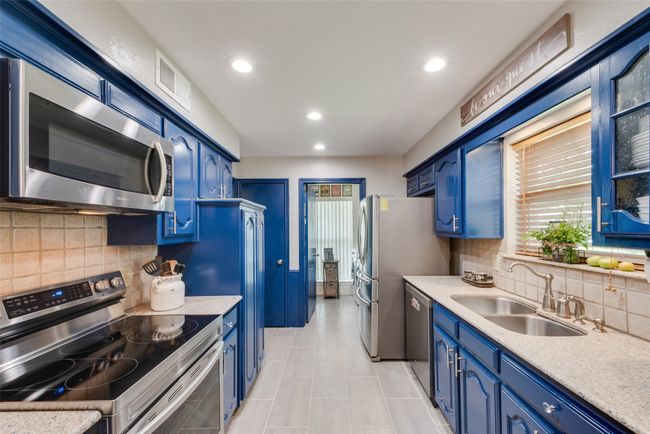 Kitchen with stainless steel appliances, blue cabinets, a sink, light countertops, and backsplash | Image 15