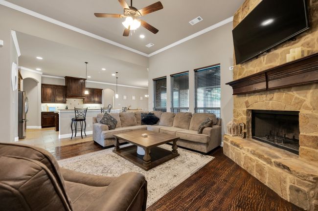 Living area featuring a ceiling fan, ornamental molding, recessed lighting, a stone fireplace, and arched walkways | Image 13