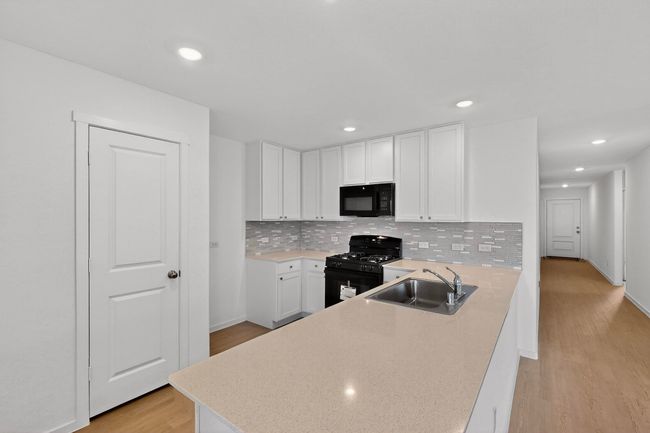 Kitchen with black appliances, a sink, light wood-style floors, white cabinetry, and recessed lighting | Image 8