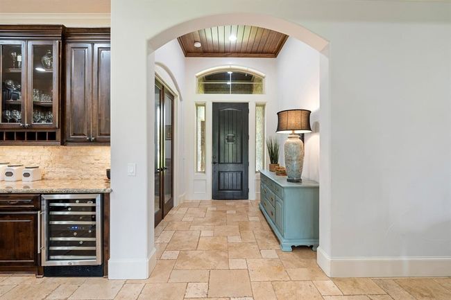 A look back at the grand front door showcases the abundance of natural light that fills the Foyer through the sidelights and transom above. The wood-paneled ceiling adds warmth and draws the eyes upward. The glass-paned double doors to the left lead to the home’s Study. | Image 6