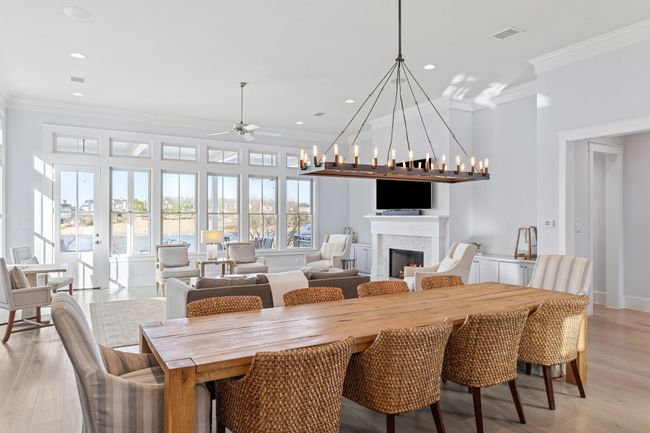 Dining room with ceiling fan with notable chandelier, crown molding, a lit fireplace, and light wood finished floors | Image 9