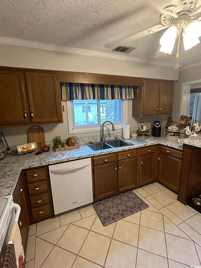 Kitchen with dishwasher, range, crown molding, a textured ceiling, and light tile patterned floors | Image 8