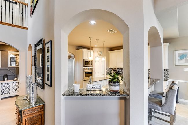 Kitchen with decorative backsplash, white cabinets, dark stone counters, and appliances with stainless steel finishes | Image 16