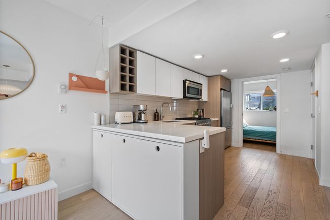 Kitchen with open shelves, light wood-style floors, a peninsula, stainless steel appliances, and backsplash | Image 11
