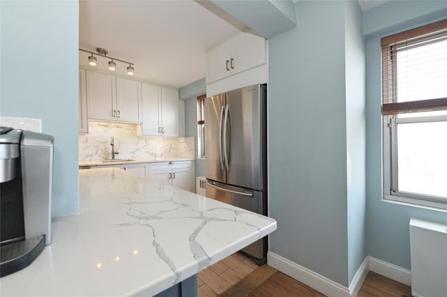 Kitchen with freestanding refrigerator, white cabinetry, tasteful backsplash, and a sink | Image 7