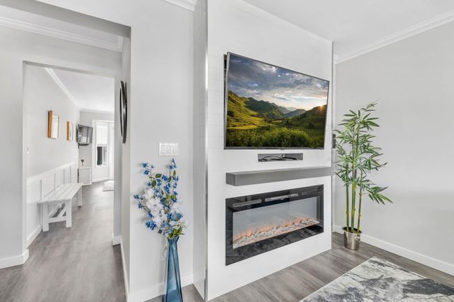 Living room featuring a glass covered fireplace, baseboards, ornamental molding, and wood finished floors | Image 10