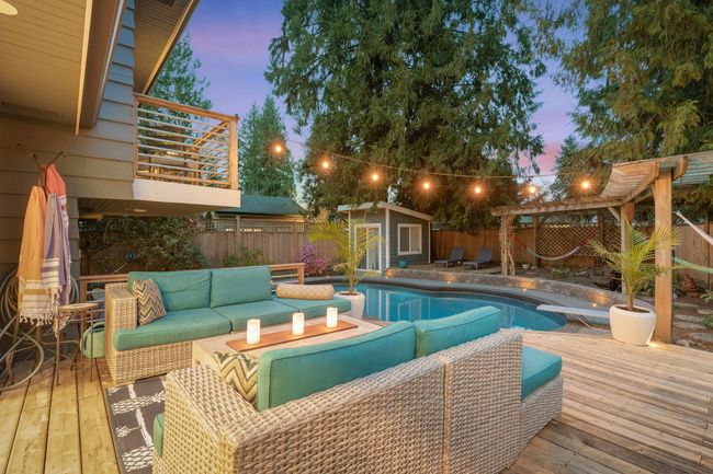 Pool at dusk featuring a fenced in pool, a diving board, an outdoor living space, a fenced backyard, and an outbuilding | Image 38