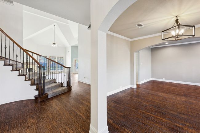 Entryway featuring lofted ceiling, dark hardwood / wood-style flooring, ceiling fan with notable chandelier, and ornamental molding | Image 11