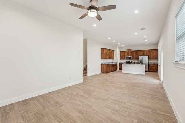 Unfurnished living room featuring stairway, baseboards, recessed lighting, ceiling fan, and wood plank tile floor | Image 10