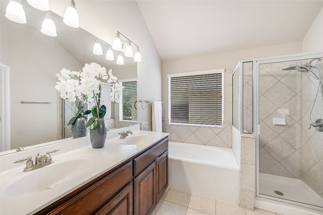 Bathroom featuring a garden tub, a stall shower, double vanity, tile patterned floors, and vaulted ceiling | Image 16