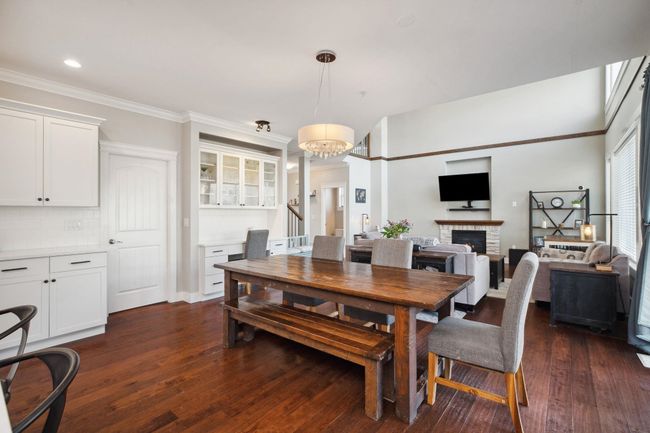 Dining area featuring a notable chandelier, ornamental molding, dark wood-style floors, recessed lighting, and a lit fireplace | Image 8