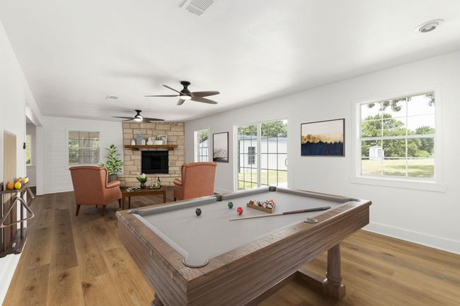 Spacious family room featuring a cozy stone fireplace, large windows with scenic views, and elegant flooring, perfect for relaxation and entertainment. | Image 27