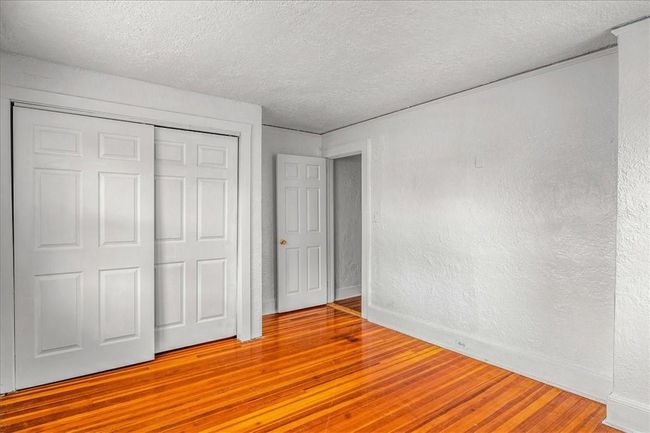 Unfurnished bedroom featuring a textured ceiling, hardwood / wood-style flooring, and a closet | Image 12